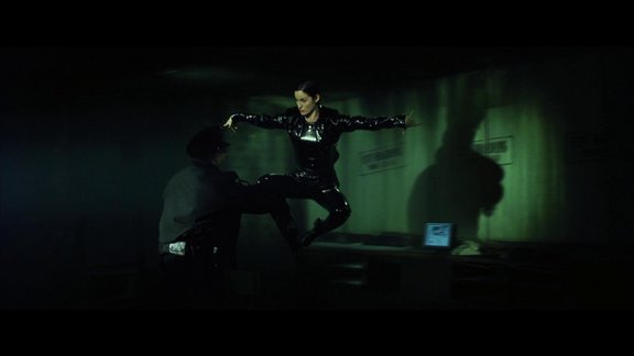Trinity leaps into the air, the film pausing to pan around her frozen mid leap, preparing to kick a policeman.